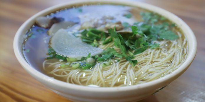 A bowl of noodles, vegetables, with bone broth